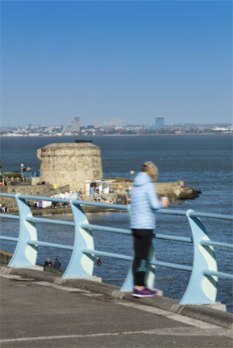 Woman leaning over a rail looking towards the sea